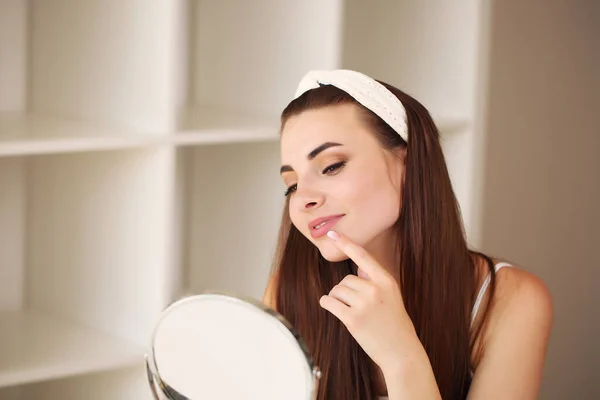Schoonheid, huidverzorging en mensen concept - lachend jong meisje suggereert schoonheid voor op het gezicht in de kamer — Stockfoto