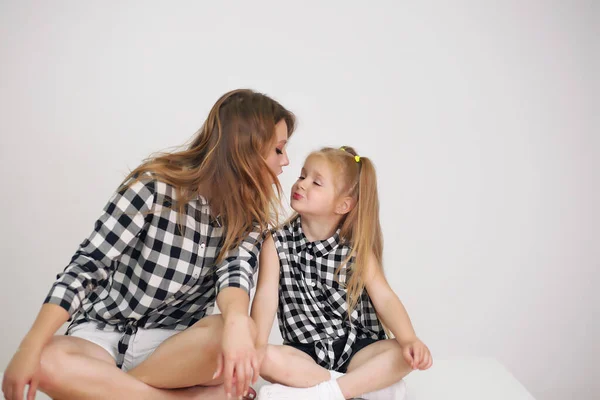 Glücklich liebende Familie. Mutter und ihr Töchterchen küssen und umarmen sich im Zimmer. Frau und Mädchen mit Lockenwicklern auf dem Kopf. — Stockfoto
