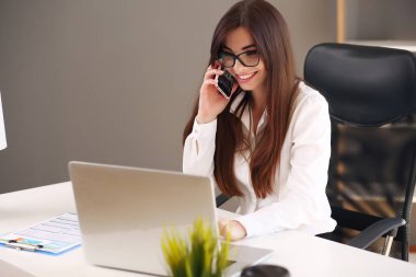 Genç bir kadın cep telefonuyla konuşurken not alıyor..