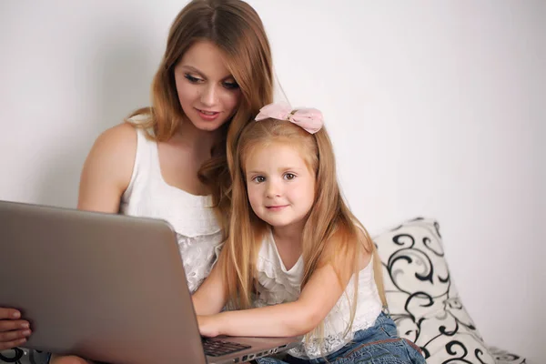 young mother works with her daughter on the pc at home