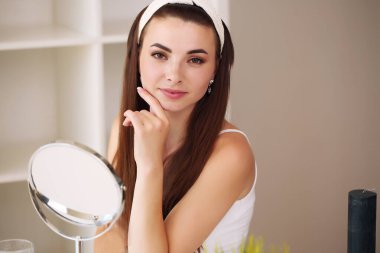 Duştan sonra banyoda çekici genç bir kadın aynanın önünde yüz kremiyle duruyor. Kadınlar umursar.