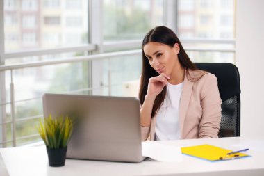 Laptop bilgisayarında çalışan çekici, gülümseyen genç bir kız.