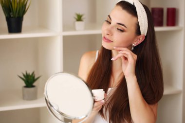 Genç, güzel, sağlıklı bir kadının yüzü aynaya bakıyor.