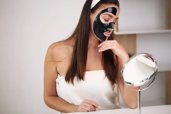 Wanita muda dan cantik dengan masker kupas hitam di wajahnya setelah mandi — Stok Foto