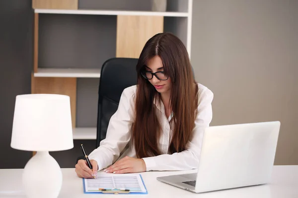 Jovem mulher de negócios trabalhando em seu escritório usando um laptop — Fotografia de Stock