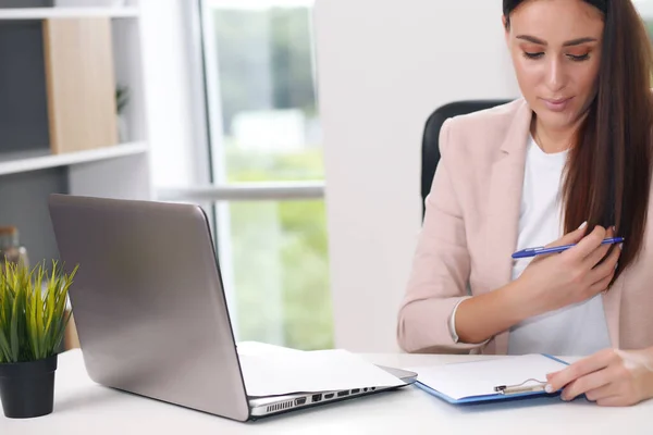 Young female content manager makes notes with a pen