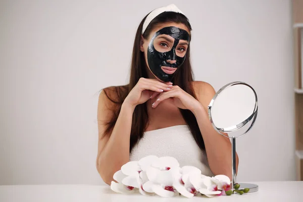 Piękna kobieta z oczyszczającą czarną maską na twarzy. — Zdjęcie stockowe