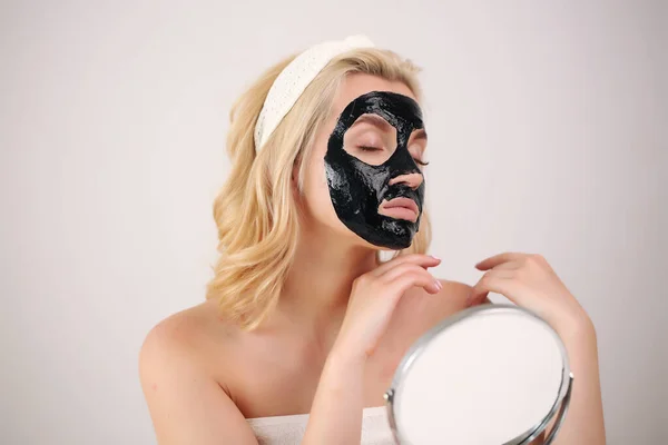 girl wearing a black mask on her face caring looking in the mirror