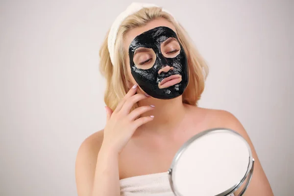 girl wearing a black mask on her face caring looking in the mirror