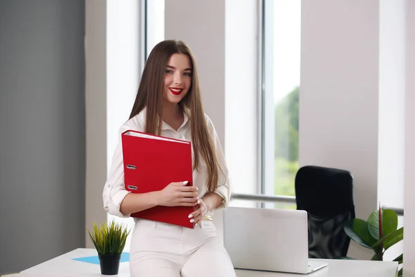 Beyaz bir ofiste dizüstü bilgisayarla masada oturan genç bir kadın. öğrenci ya da iş kadını — Stok fotoğraf