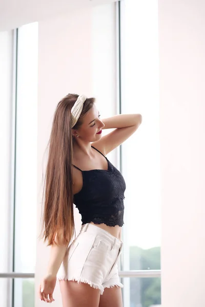 Junges schönes Mädchen mit langen lockigen Haaren trägt kurze Mini-Jeans und posiert — Stockfoto