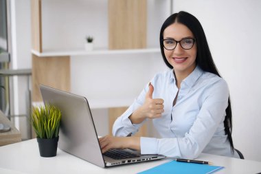 Ofisteki genç iş kadını başparmağını kaldırıyor.