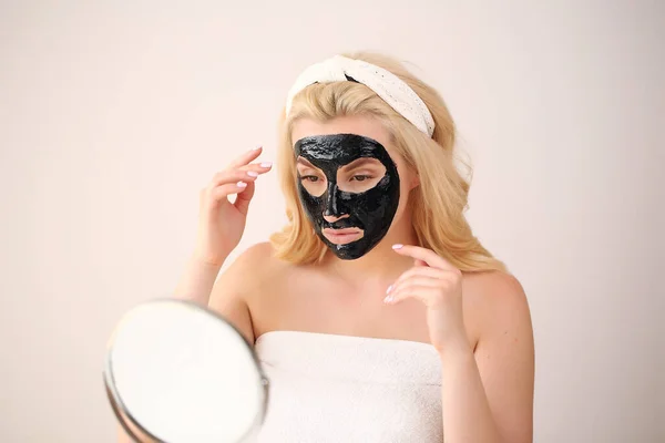 Gadis mengenakan masker hitam di wajahnya peduli melihat di cermin — Stok Foto