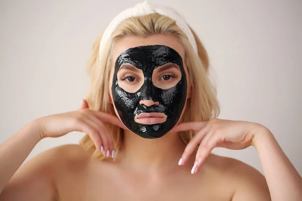 Vrouw gezicht met zwarte peeling masker op huid.applying cosmetische masker op gezicht. — Stockfoto