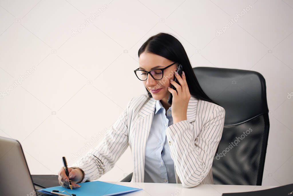 Happy businesswoman talking on mobile phone while analyzing weekly schedule in her notebook.