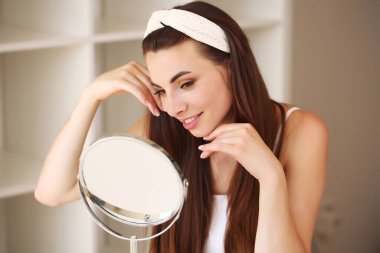 Genç, güzel, sağlıklı bir kadının yüzü aynaya bakıyor.