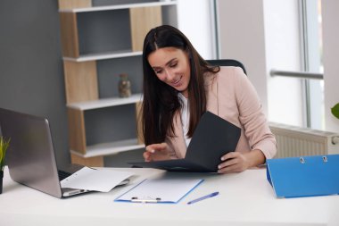 Güzel genç iş kadını modern ofiste oturuyor, esmer.