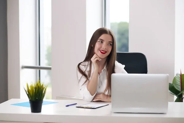 Mulher de negócios sentada em uma mesa com um laptop e olhando para longe no escritório — Fotografia de Stock