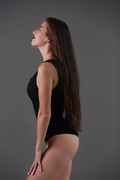 Modelo com pele bonita. A menina em um bodysuit preto toma uma pose modelo. — Fotografia de Stock
