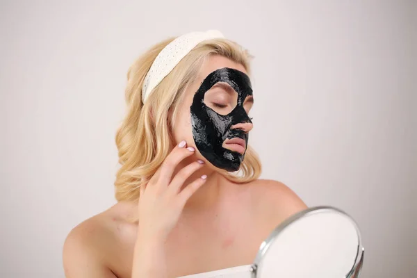 Hautpflege. Porträt eines jungen Mädchens mit schwarzer Maske im Gesicht. — Stockfoto