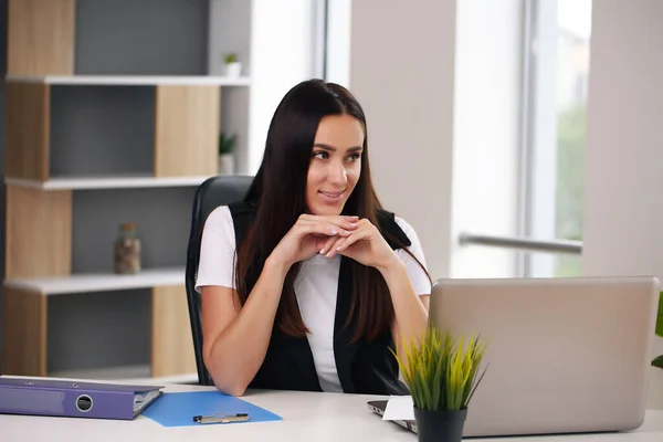 Młoda, szczęśliwa bizneswoman w biurze, pracująca na laptopie — Zdjęcie stockowe