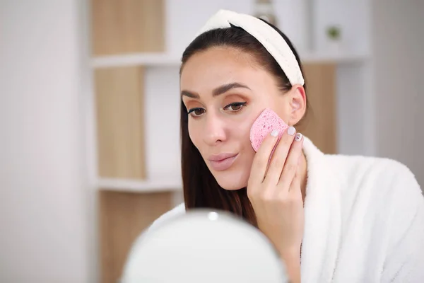Brunette dalam mandi mencuci dari makeup dengan spons merah muda — Stok Foto