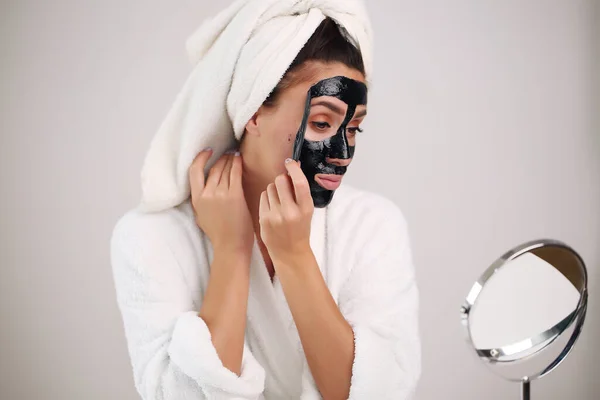 Gyönyörű nő leveszi a tisztító maszkot az arcáról. — Stock Fotó