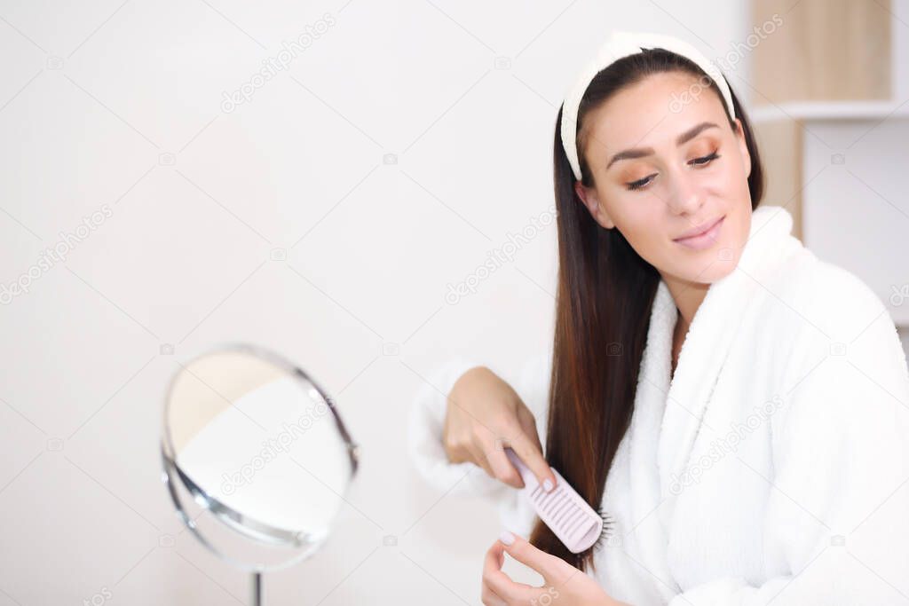 brown hair in a robe, she combs her hair with brushes with jagged smiles,