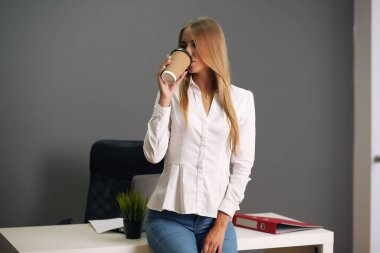 Ofisteki masasında oturuyor. Ofiste oturan mutlu iş kadını.