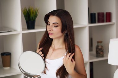 Genç, güzel, sağlıklı bir kadının yüzü aynaya bakıyor.