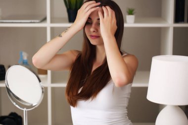 Evde oturuyor, aynaya bakıyor, gülüyor ve eğleniyor. Sabah cilt bakım rejimi.