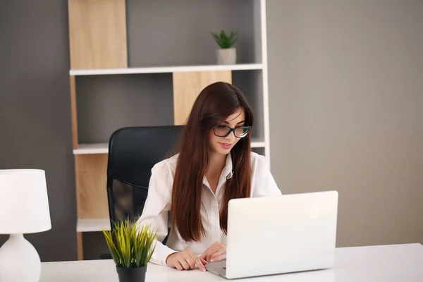 Piękna kobieta biznesu używa laptopa i uśmiecha się podczas pracy w biurze — Zdjęcie stockowe
