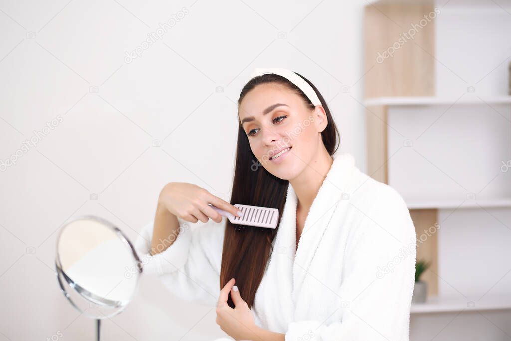 brown hair in a robe, she combs her hair with brushes with jagged smiles,