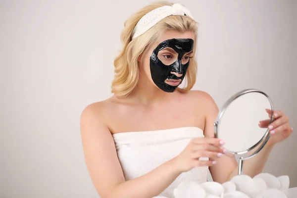 Φροντίδα δέρματος. Πορτρέτο ενός νεαρού κοριτσιού με μια μαύρη μάσκα στο πρόσωπό της. — Φωτογραφία Αρχείου