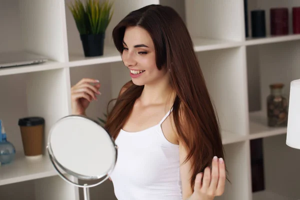 Όμορφη γυναίκα αγγίζει λείο δέρμα στο σπίτι μπροστά από έναν καθρέφτη — Φωτογραφία Αρχείου