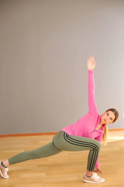 Ung sport glad sexig blond flicka i gröna leggings och rosa topp gör yoga motion — Stockfoto