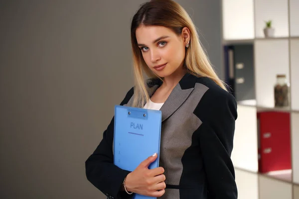 Jovem menina olhando para a câmera enquanto segurando documentos — Fotografia de Stock