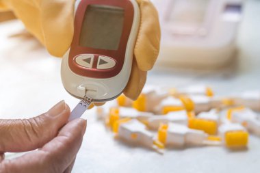 İnsanlar evde Glucometer ile kan şekeri seviyesini kontrol ediyor