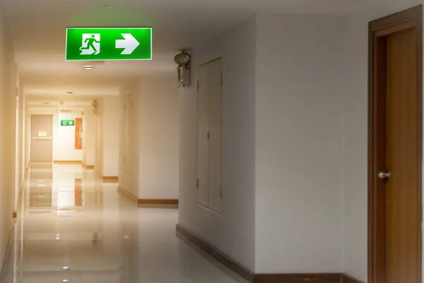 Green emergency exit sign in hotel showing the way to escape — стоковое фото