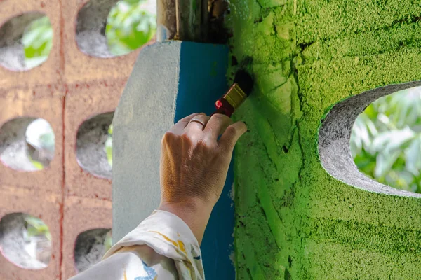 painter hand up painting a wall with paint brush