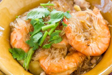 Kahverengi kil çömleğinde güveçte karides ya da sh ile pişirilmiş cam erişte.