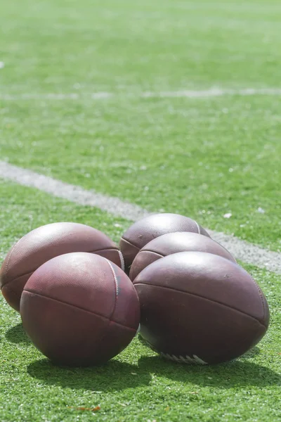 在绿场上躺着一堆真皮足球球 — 图库照片