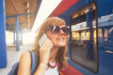 kadın Smartphone cep telefonu ile Tren İstasyonu yakınında dururken söz 