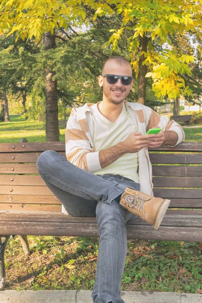 Hombre Usando Teléfono Inteligente Mientras Está Sentado Banco Madera Parque —  Fotos de Stock