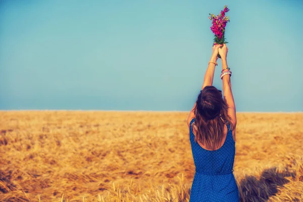 妇女举起手与野花花束在大麦草甸 — 图库照片