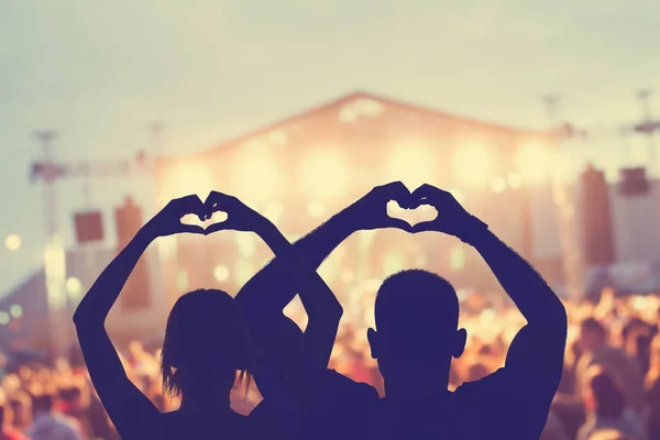 Couple making a heart-shapes at the concert