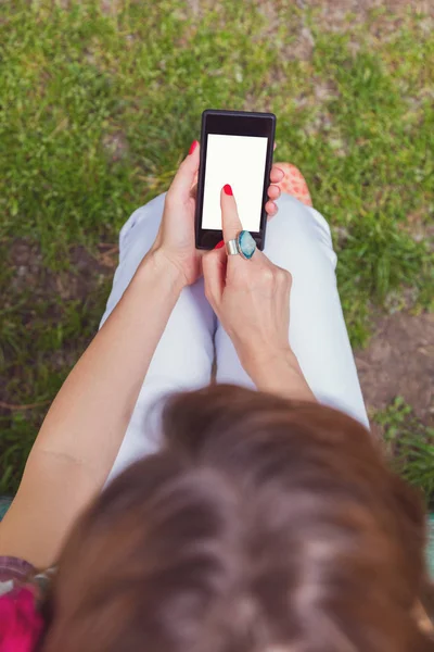 woman wearing summer clothes using smartphone while sitting in park