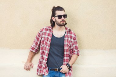 saç modeli güneş gözlüğü ve trendy kıyafetler bej duvar arka plan üzerinde poz ile yakışıklı adam 