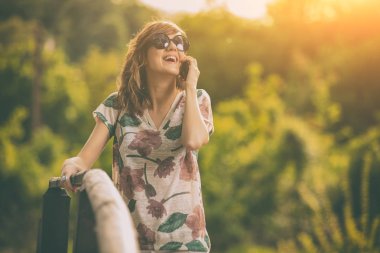 Kadın akıllı Park ahşap köprü üzerinde dururken söz