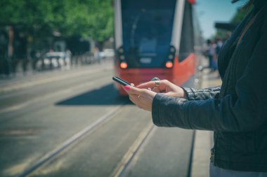 Smartphone duran tramvay istasyonunda kullanan kadın